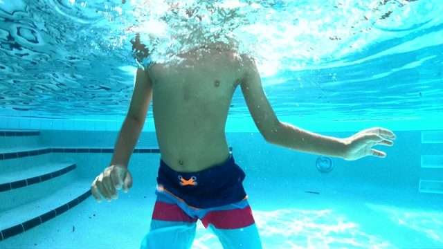 混血男孩在游泳池水下游泳视频素材