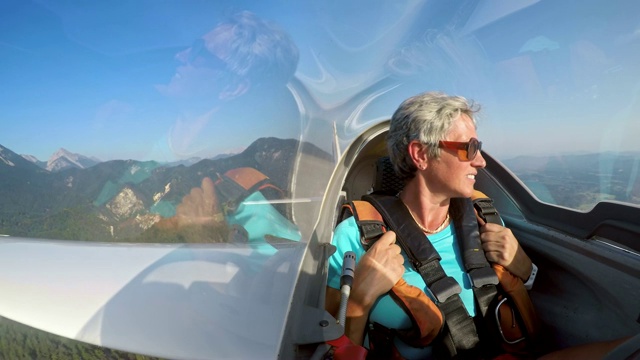 一个女人坐在滑翔机里，欣赏着下方阳光明媚的风景视频素材