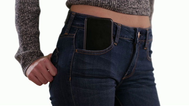 特写的年轻女子的腰部与手机在前口袋上的白色拷贝空间视频素材