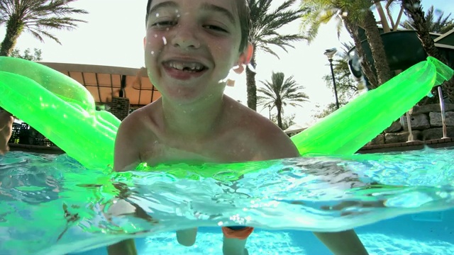 水池上的男孩笑着，游到镜头前视频素材