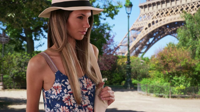 在埃菲尔铁塔附近，穿着花连身裤戴着软呢帽拿着包的漂亮女士视频素材