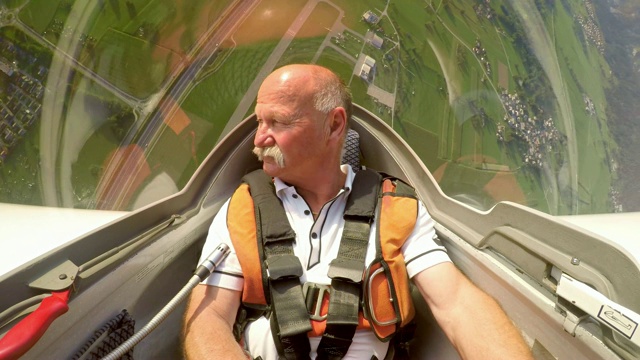 一名男性飞行员在一个阳光明媚的日子里驾驶着他的滑翔机表演特技视频素材