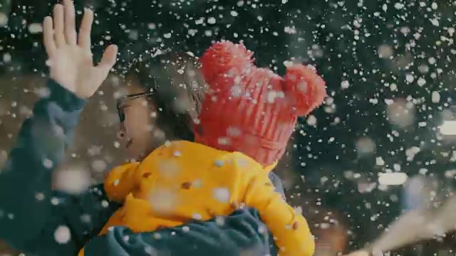 母亲和女儿玩在冬天的节日，下雪视频下载