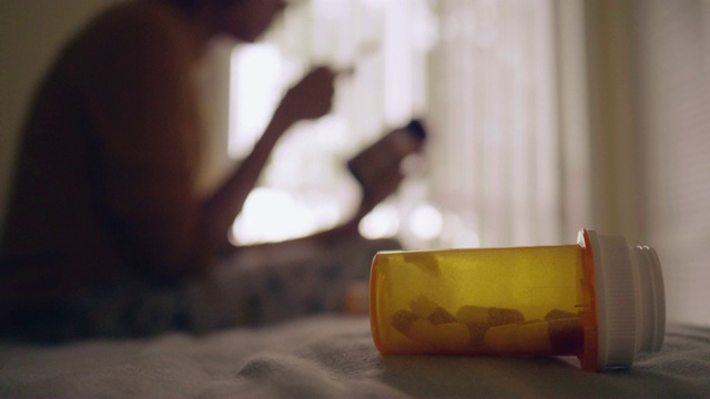 年轻的亚洲女人拿着药瓶，在卧室里讲手机视频素材
