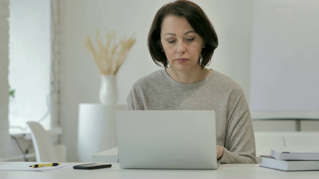 老女人用笔记本电脑完成工作后离开视频素材