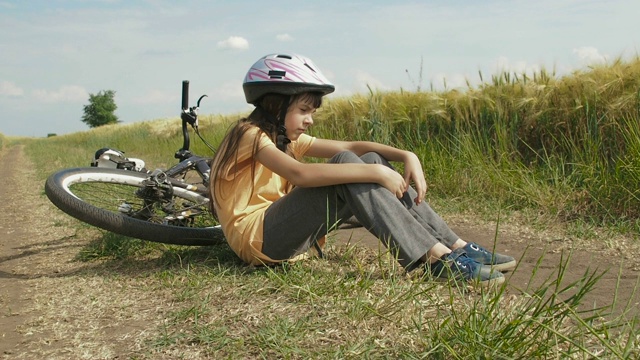 累了骑自行车。骑着自行车的孩子倚靠在大自然上。视频下载