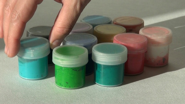 手拿并放入绿松石丙烯酸水粉颜料。家庭作业，艺术家的作品视频素材