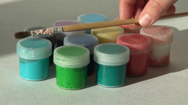 艺术家把画笔放在装丙烯酸水粉颜料的罐子上视频素材