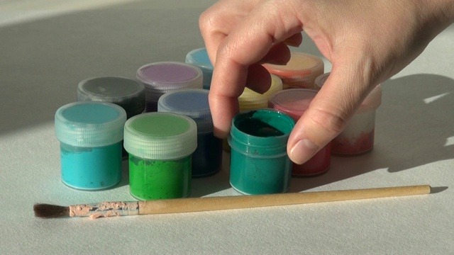 手拿，打开并放罐绿色丙烯酸水粉颜料。作业,艺术家的作品视频素材