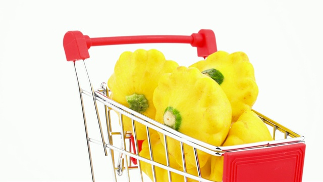 超市手推车的特写与黄色pattypan南瓜。购物车在画面中移动。孤立在白色背景上。视频下载