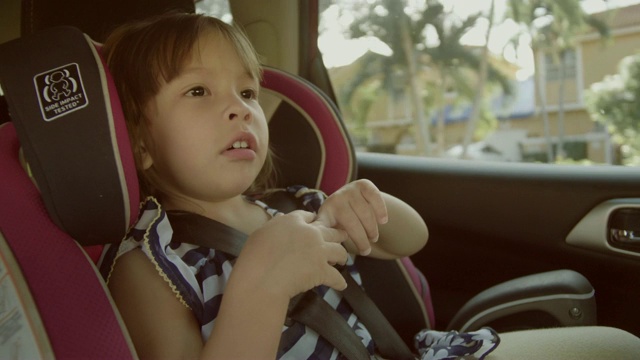 在儿童汽车安全方面。小女孩坐在特制的汽车座椅上视频素材