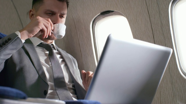 西装男在飞机上用笔记本电脑工作视频素材