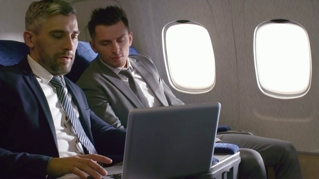 在飞机上用笔记本电脑工作的商人视频素材