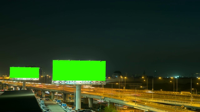 泰国曼谷高速公路上以城市为背景的夜间绿色广告牌。时间流逝。视频素材