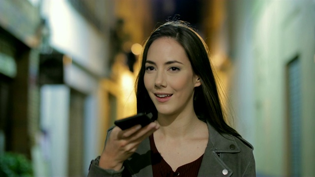 一个在晚上使用电话语音识别的女人视频素材