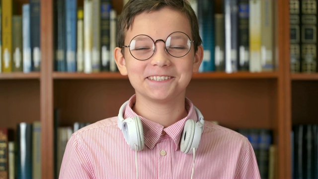 这张照片拍摄的是一个可爱的小男孩站在图书馆的书架旁边竖起大拇指视频下载