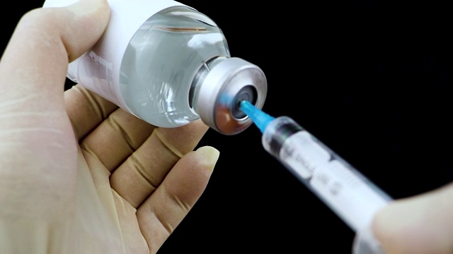 用药针头注射器用药，医学概念流感注射疫苗小瓶剂量皮下注射治疗疾病护理医院预防免疫接种疾病。黑色背景视频素材