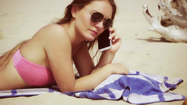 女人放松在沙滩上讲4K电话视频素材
