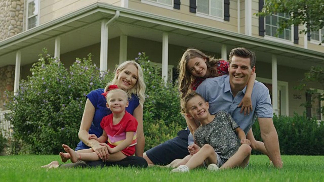 快乐嬉戏的家庭在房子附近的草坪上放松的肖像/ Pleasant Grove，犹他州，美国视频素材