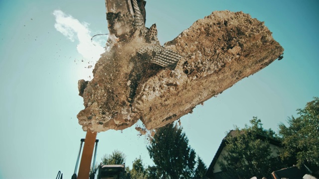 SLO MO挖掘机在阳光下奋力碾碎空中的混凝土块视频素材