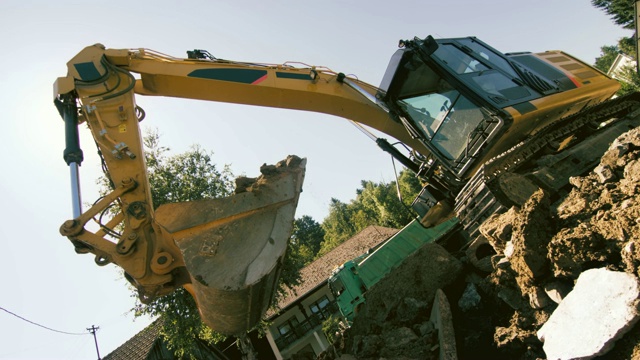 SLO MO挖掘机在阳光下抓取建筑工地的泥土和碎片视频素材