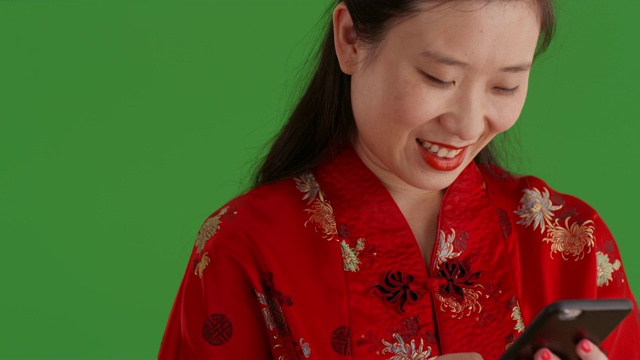 快乐的亚洲女孩使用智能手机阅读绿色屏幕上的文本的特写视频下载