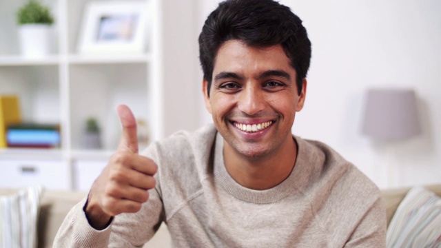 在家里的快乐微笑的年轻印度男人的肖像视频下载