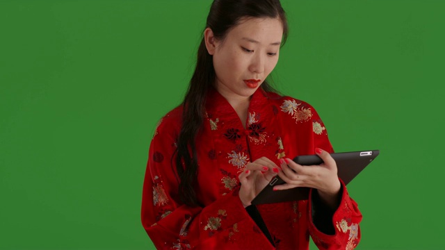 现代亚洲女性在绿色屏风前使用便携式平板设备视频下载