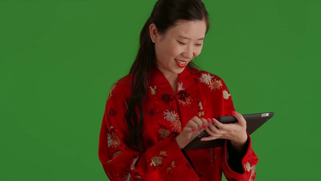 快乐的亚洲女人用平板电脑设备阅读绿色屏幕上的信息视频下载