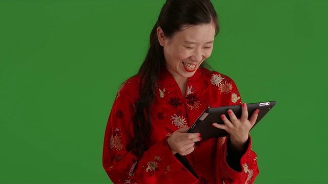 自信的亚洲女性在绿色屏幕上与便携式平板设备互动视频下载