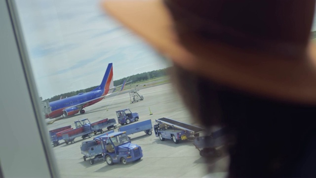 铜。年轻的混血千禧女凝视着终端机窗口外的跑道上的飞机。视频素材