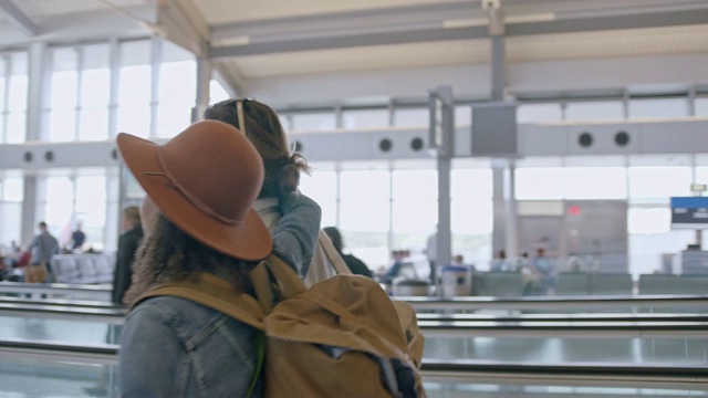 时髦的年轻混血女子挽着男友走过机场航站楼。锅。视频素材