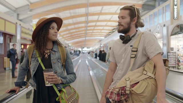 形形色色的千禧一代情侣站在机场候机楼的人行道上谈笑风生。视频素材