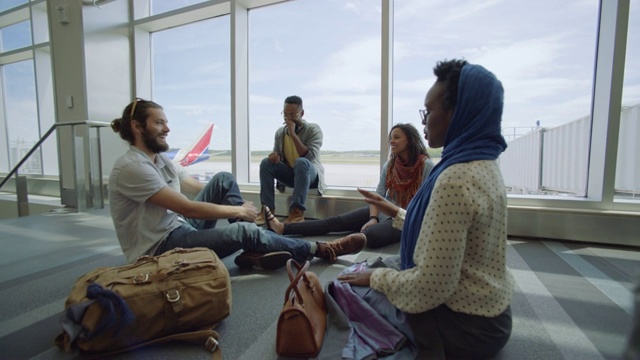 当其他旅客通过机场登机口时，各种各样的千禧一代在机场登机口笑着放松。视频素材