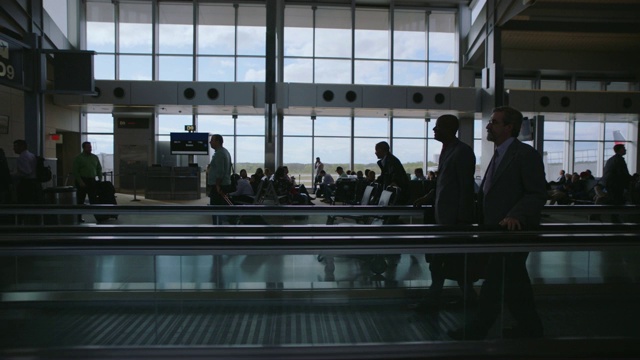 商务人士在机场候机楼的移动走道上穿梭。视频素材