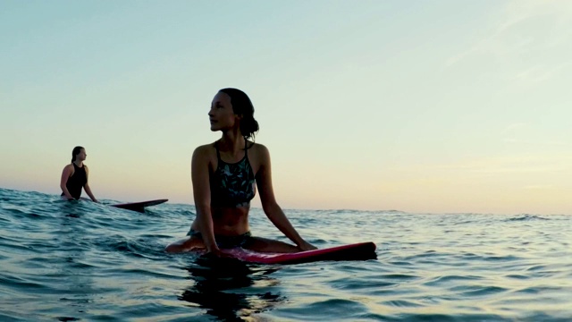 冲浪妇女在大西洋在夏季傍晚在日落冲浪板视频素材