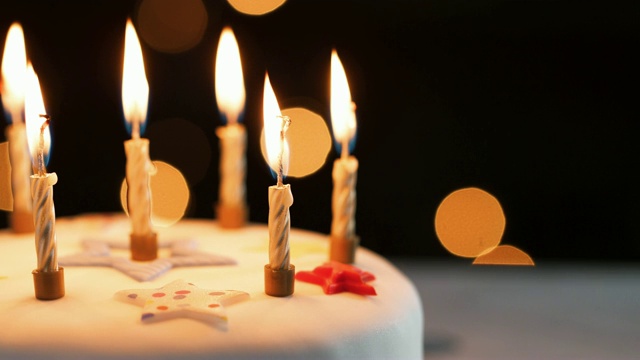 近点蜡烛在一个白色的，装饰的生日蛋糕，吹灭，散焦灯在背景视频下载
