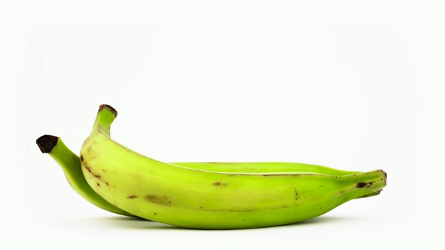 两根绿色烹饪香蕉。在转盘上旋转。孤立在白色背景上。特写镜头。宏。视频下载