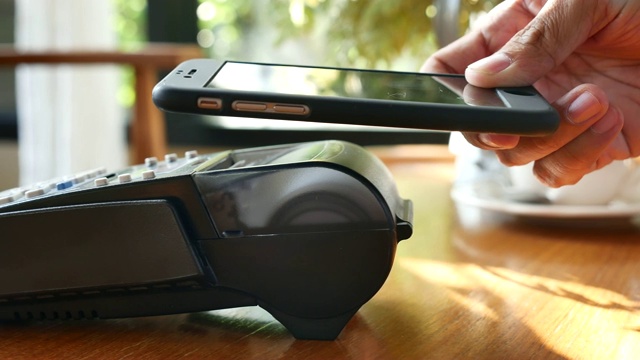 一名女性在咖啡馆用智能手机支付NFC技术视频下载