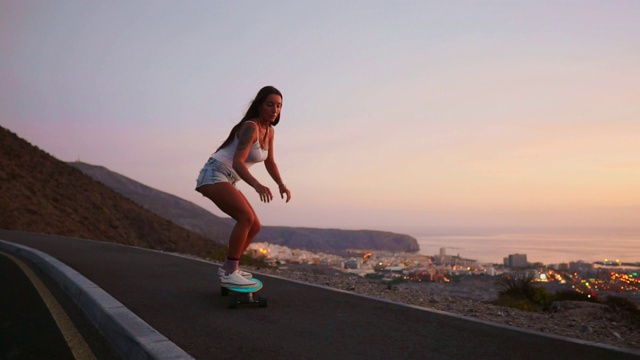 夕阳下，美丽的女孩在路上玩滑板视频素材