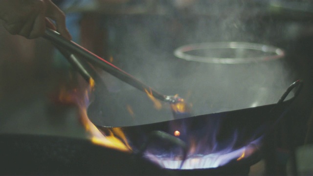 用平底锅在燃烧的炉子上烹饪，4k慢动作视频素材
