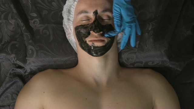 黑色面具。顶视图放松的年轻人使用一个黑色面具在水疗中心视频素材