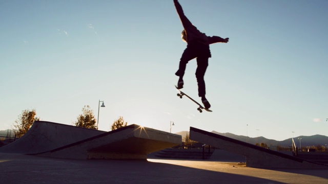 一个十几岁的白人男孩表演一个正常的脚奥利与他的滑板在滑板公园的差距视频下载