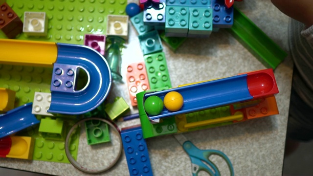 小孩子在室内玩许多五颜六色的塑料玩具。视频下载