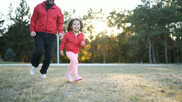 爸爸和小女儿在公园里跑步视频素材