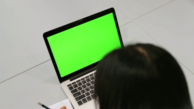 女人看着绿色屏幕的笔记本电脑视频素材