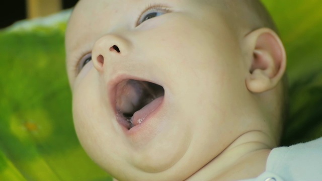 一个快乐的婴儿看着相机和微笑在慢镜头的特写。视频下载