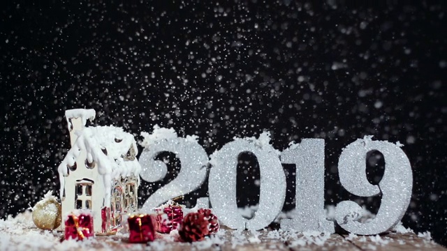 2019年圣诞节装饰和可爱的房子装饰。雪在黑色背景的慢动作视频下载