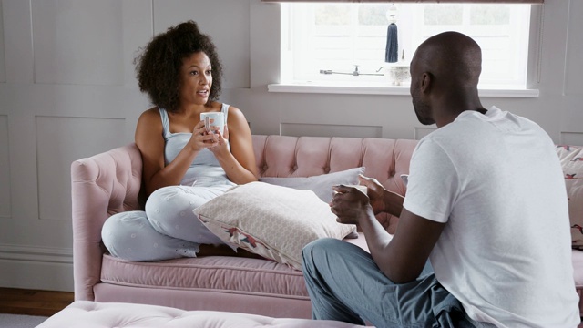 年轻的混血夫妇在一起放松，喝着咖啡，在他们的客厅里聊天视频素材