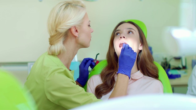 牙医用口镜检查病人的牙齿。口腔学家和耐心视频素材